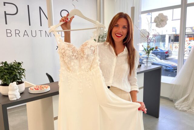 Katharina Pins zeigt in ihrem Laden ein Kleid am Bügel in einem gebrochenen Weiß.