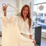 Katharina Pins zeigt in ihrem Laden ein Kleid am Bügel in einem gebrochenen Weiß.