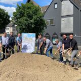 Menschen stehen um einen Erdhaufen auf dem Kleinen Markt in Schwerte. Alle halten zum ersten Spatenstich Schaufeln in der Hand.
