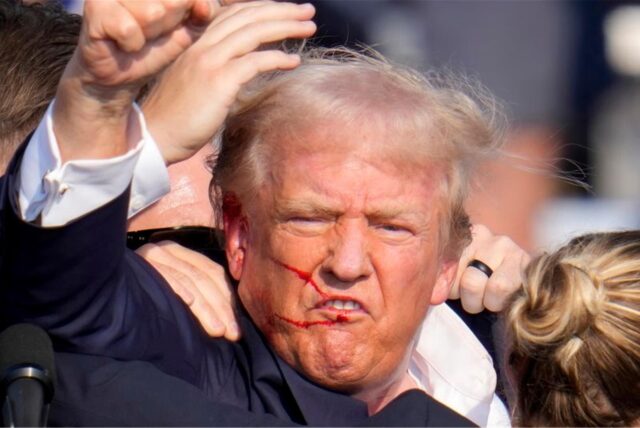 Der republikanische Präsidentschaftsbewerber und ehemalige US-Präsident Donald Trump gestikuliert, während er von Agenten des US-Geheimdienstes Secret Service umringt wird, die ihm bei einer Wahlkampfveranstaltung von der Bühne helfen.