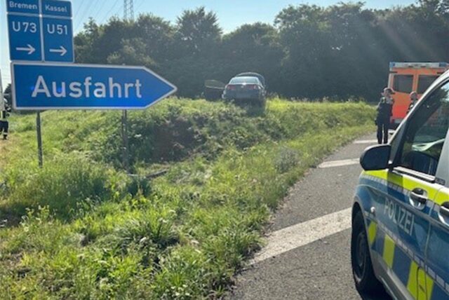 Ein Auto steht auf der Wiese neben der A1-Ausfahrt in Schwerte. Am Straßenrand stehen die Polizei und ein Rettungswagen.