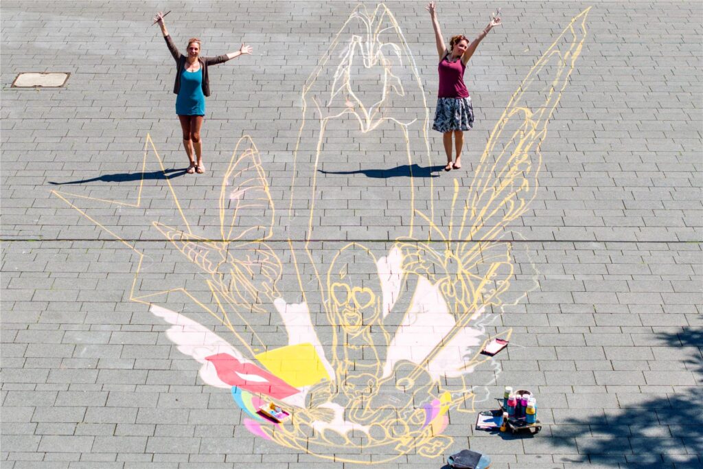 Lydia (l.) und Vanessa Hitzfeld malen ein riesiges Taylor-Swift-Bild vor dem Hans-Sachs-Haus in der Innenstadt von Gelsenkirchen. 