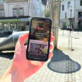 Eine Hand hält ein Smartphone in die Kamera, das die Internetseite von MyCityHunt zeigt.