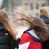 Starker Wind wirbelt die Haare von zwei jungen Frauen auf.