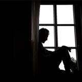 Ein Mann sitzt nachdenklich vor einem Fenster.