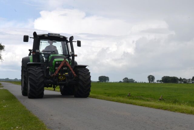  Ein Landwirt fährt mit seinem Trecker über einem Wirtschaftsweg.