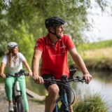 Zwei Radfahrer auf einer Radtour entlang eines Flusses.