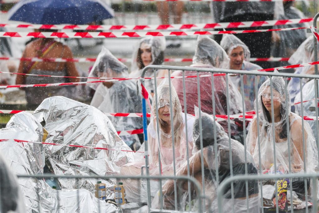 Ein kurzer und heftiger Regenschauer kühlt die wartenden Fans ab. Ein kurzer und heftiger Regenschauer kühlt die wartenden Fans ab.