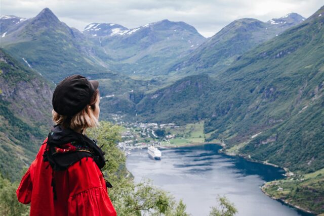 Eine Frau mit einer roten Jacke an einem Fjord in Norwegen
