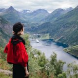 Eine Frau mit einer roten Jacke an einem Fjord in Norwegen