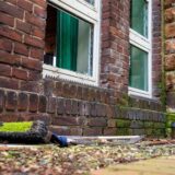 Vor einem zerborstenen Glasfenster der Christuskirche in Herten liegt nach einem Unfall ein Besen auf dem Boden.