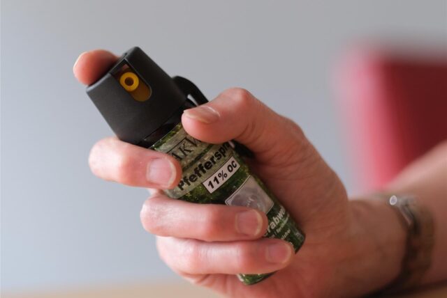 Eine Hand hält eine Pfefferspray-Dose. Der Zeigefinger liegt auf dem Auslöser.