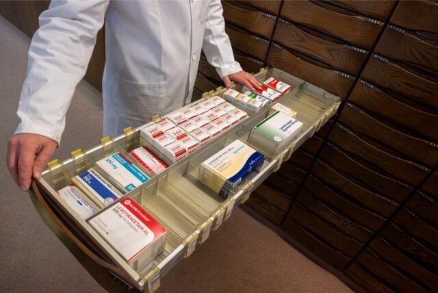 Ein Apotheker zieht eine Schublade mit Medikamenten aus.
