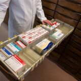 Ein Apotheker zieht eine Schublade mit Medikamenten aus.