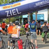 Mehrere Radfahrerinnen und Radfahrer überqueren die Ziellinie bei der NRW-Radtour 2024 in Fröndenberg am Samstag (20. Juli)