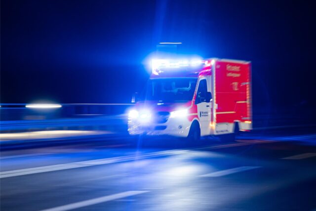 Ein Rettungswagen der Feuerwehr fährt mit Blaulicht durch eine Straße.