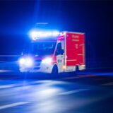 Ein Rettungswagen der Feuerwehr fährt mit Blaulicht durch eine Straße.