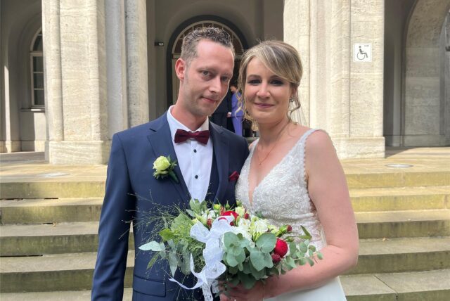 Svea und David Anders stehen frisch verheiratet vor dem Rathaus in Schwerte.