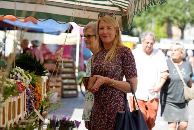 Eine Frau in einem bunten Kleid steht an einem Blumenstand am Dortmunder Wochenmarkt.
