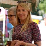 Eine Frau in einem bunten Kleid steht an einem Blumenstand am Dortmunder Wochenmarkt.