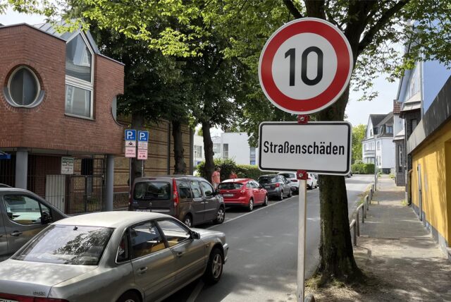 Neben einer Straße in Unna steht ein Baustellenschild, das die Geschwindigkeit auf zehn km/h beschränkt.