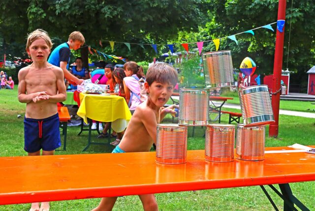 Ein Junge wirft beim Bergfest im Elsebad in Schwerte-Ergste einen Ball gegen einen Turm aus Dosen.