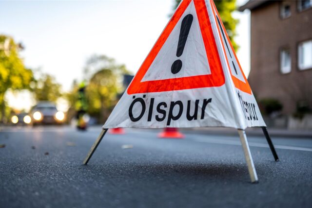 Ein Warnschild mit der Aufschrift „Ölspur“ auf der Fahrbahn (Symbolbild)