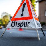 Ein Warnschild mit der Aufschrift „Ölspur“ auf der Fahrbahn (Symbolbild)