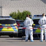 Beamte der Spurensicherung stehen hinter einer Absperrung der Polizei.