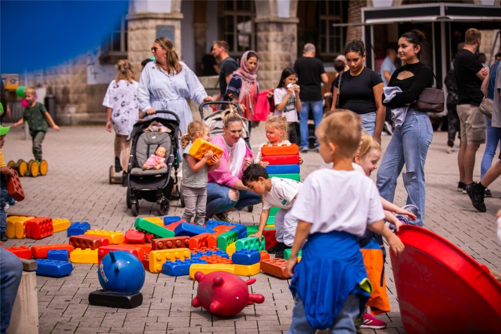 Kinder spielen mit übergroßen Duplo-Steinen und anderen Spielgeräten in der Innenstadt von Menden