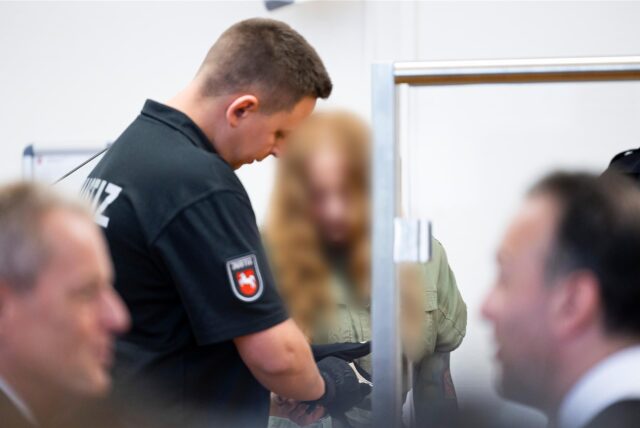 Angeklagte bekommt Handschellen von einem Wachmann abgenommen.