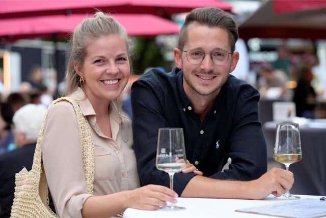 Eine Frau und ein Mann trinken beim Weinfest in Dortmund ein Glas Weißwein.