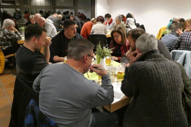 Menschen sitzen beim Kneipenquiz in Werne in Gruppen zusammen.