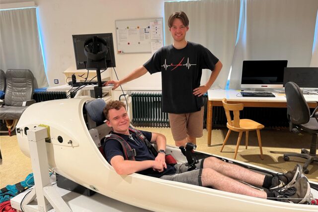 Alexander Konschak und Lars Rothholz vom LSV Ruhr-Lenne Iserlohn: Alexander sitzt im Flugsimulator, Lars steht daneben.