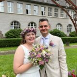 Marina und Julian Boneberger stehen frisch verheiratet vor dem Bogen am Rathaus in Schwerte.