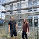 Hausverwalterin Jill Aschrich und Bauleiter Etnik Asani stehen vor einem der drei Neubauten im Dortmunder Westen. Vermietungsbeginn ist am 1. Dezember 2024.