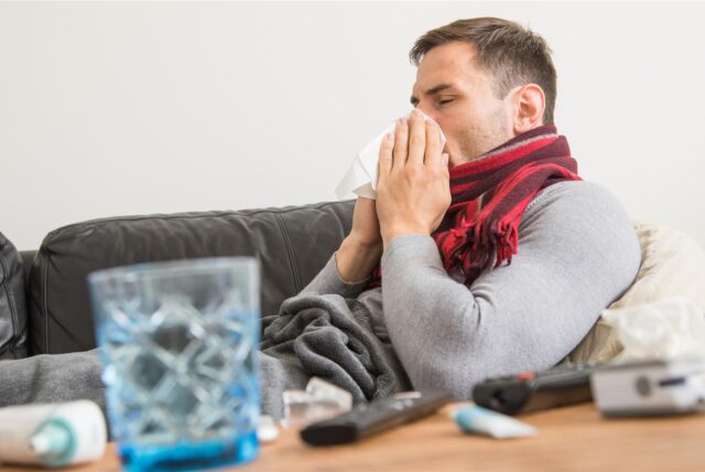 Mann auf Sofa mit Erkältung