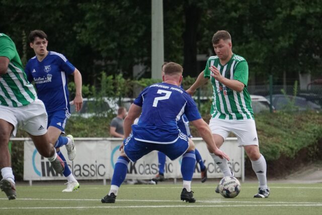 SG Selms Robin Coerdt (r.) läuft mit Ball auf eine Ahsener Gegenspieler zu.
