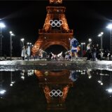Der Pariser Eifelturm geschmückt für Olympia, spiegelt sich in einer Regenpfütze.