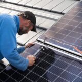 Ein Mann installiert eine PV-Anlage auf einem Dach.