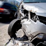 Ein beschädigtes Auto steht an am Straßenrand, ein anderes Auto fährt weg.