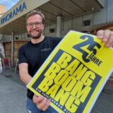 Markus Dollenkamp, Geschäftsführer beim Verlag Rubens, und Guido Rottstegge, Geschäftsführer des Kinorama, halten vor dem Kinorama in Unna einen Becher Popcorn und ein Filmplakat mit der Aufschrift „25 Jahre Bang Boom Bang“.