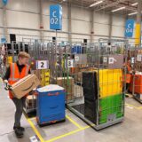 Im Amazon-Verteilzentrum Unna trägt eine Mitarbeiterin mit einer Warnweste ein Paket