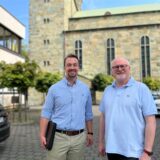 Stefan Spallek (l.) und Paul Mandelkow (Verwaltungsleiter und Pfarrer im Pastoralen Raum Unna) stehen vor der Katharinenkirche und dem benachbarten Pfarrheim