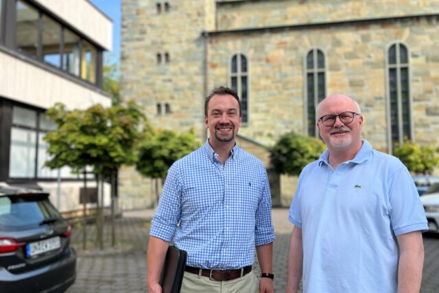 Stefan Spallek (l.) und Paul Mandelkow (Verwaltungsleiter und Pfarrer im Pastoralen Raum Unna) stehen vor der Katharinenkirche und dem benachbarten Pfarrheim