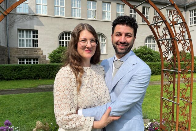 Sara und Karsten stehen frisch getraut vor dem Bogen am Schwerter Rathaus.