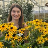 Neele Klönne steht inmitten bunter Blumen im Gartencenter Röttger.