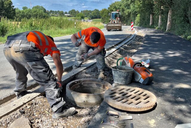 An der Türkenstraße in Unna arbeiten zwei Bauarbeiter. Im Hintergrund steht ein Radlader