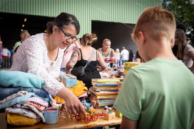 Eine Frau schaut sich Ware bei einem Flohmarkt an.