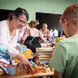 Eine Frau schaut sich Ware bei einem Flohmarkt an.
